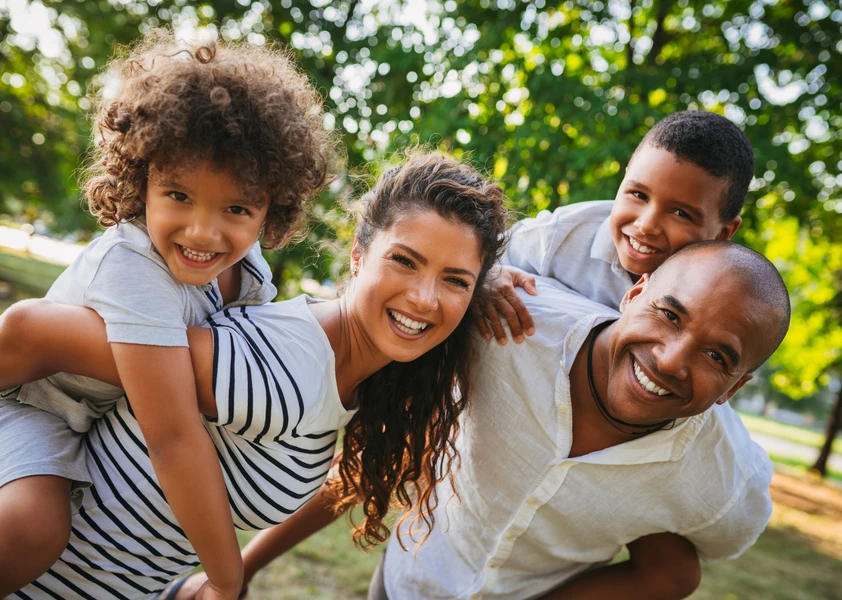 Famille souriante réunie dans un parc.
